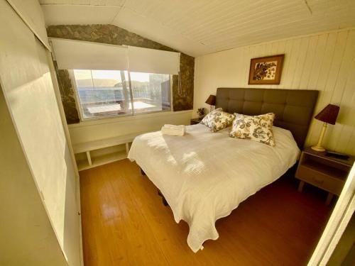 a bedroom with a large bed with a window at Bahia Inglesa cabaña frente al mar WI-Fi satéliteTv agua caliente in Bahia Inglesa
