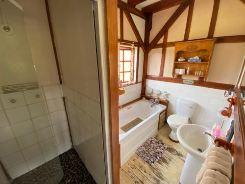 y baño con bañera, aseo y lavamanos. en Bohemian Garden Cottages, en Kaapsehoop