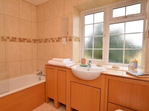 a bathroom with a sink and a tub and a window at 3 Bed in Smarden 58544 in Smarden