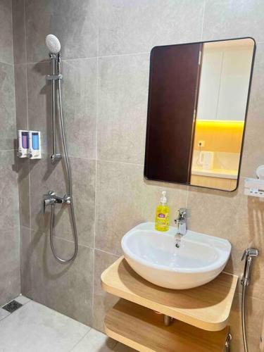 y baño con lavabo y ducha con espejo. en Wawa Guesthouse Pollux Habibie Batam Tower A 18, en Batam Centre