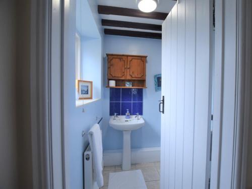 Un baño azul con lavabo y lavabo. en 3 bed in Southrepps 76795, en Northrepps