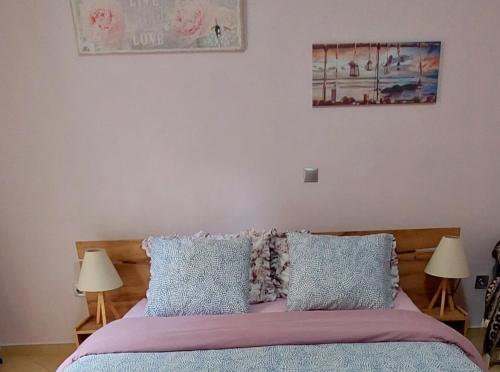 a bedroom with a bed with pillows and two lamps at Elpida's house in Spata