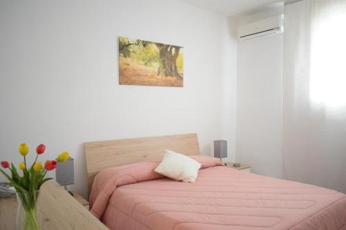 een slaapkamer met een roze bed en een vaas met bloemen bij La Casa del Carrubo in Cagliari