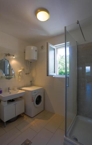 a bathroom with a washing machine and a sink at Apartman Kimi in Šilo