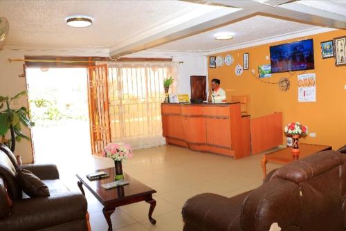 a living room with a person standing in a kitchen at PrimeRose Hotel Mubende in Mubende