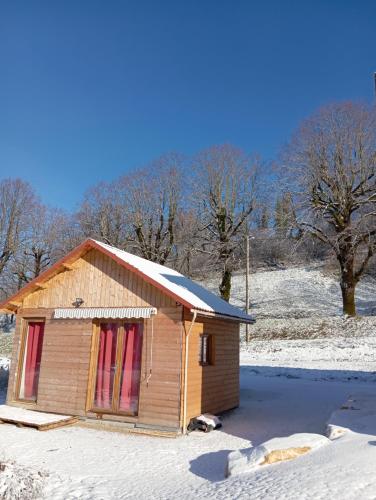 a small wooden building with snow on the roof at La p'tite maison bois du hérisson in Ménétrux-en-Joux