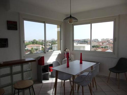 une salle à manger avec une table, des chaises et des fenêtres dans l'établissement GOELETTE appartement climatisé, équipé du wifi et parking gratuit en haute saison, à Canet