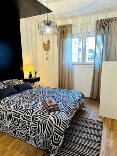 une chambre avec un lit avec une couverture noire et blanche dans l'établissement Le Haut Mabilais - Centre Rennes, à Rennes