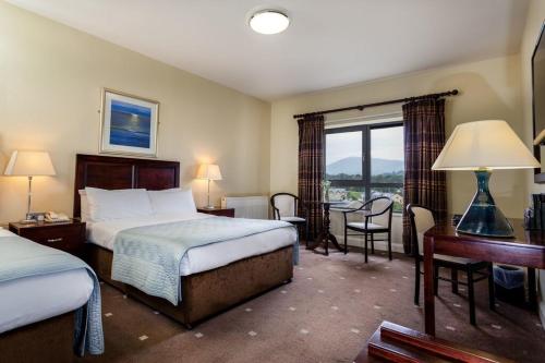 a hotel room with two beds and a desk and a window at The Kenmare Bay Hotel & Leisure Resort in Kenmare