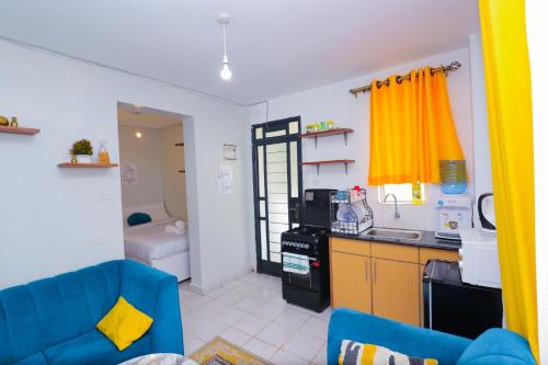 a living room with a blue couch and a kitchen at Cozy Studio along Ngong road-Nairobi in Nairobi