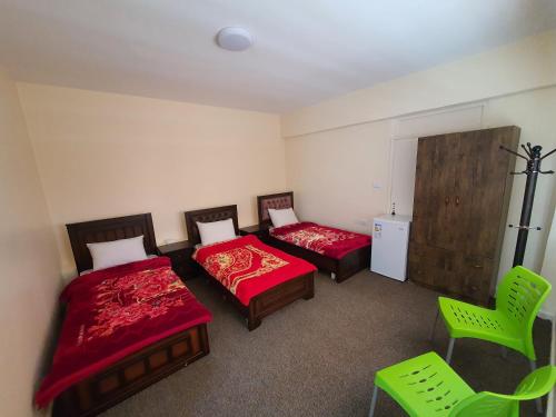 two beds in a room with green chairs at Petraone in Wadi Musa