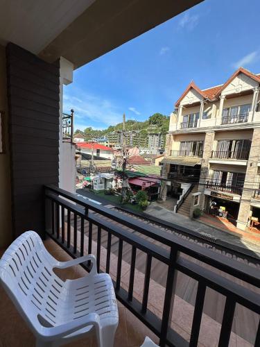 a white chair on a balcony with a view of a building at Baan Kingkeaw Thamdee Patong in Patong Beach