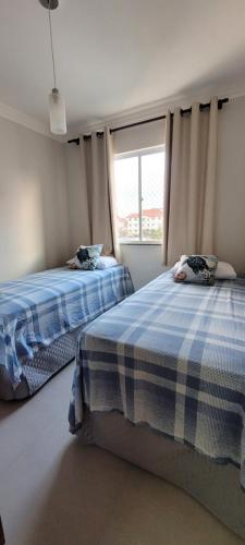 una camera da letto con due letti e una finestra di Recanto da Gabriela - Apartamento para temporada na zona sul de ilhéus a Ilhéus