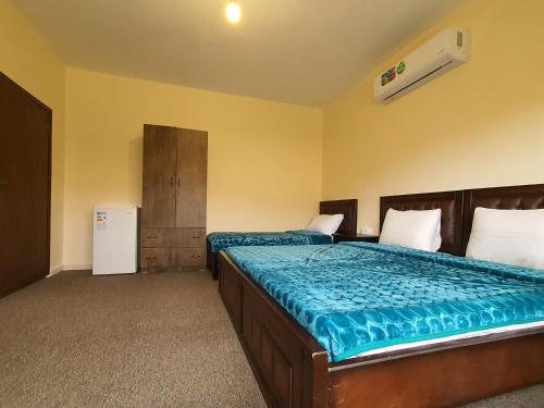 a bedroom with two beds and a refrigerator at Petraone in Wadi Musa
