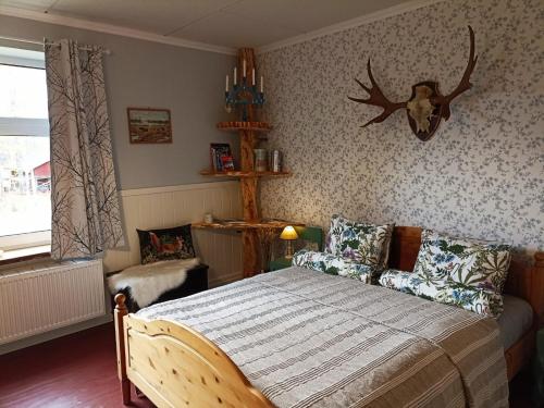 a bedroom with a bed and a deer head on the wall at Furulund in Gällö
