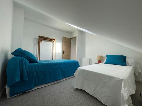 ein weißes Schlafzimmer mit einem Bett und einem Spiegel in der Unterkunft Au bal des hirondelles in Andé