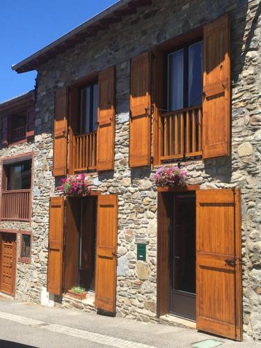 a stone building with wooden doors and windows at GITE DU TREUIL in Ignaux