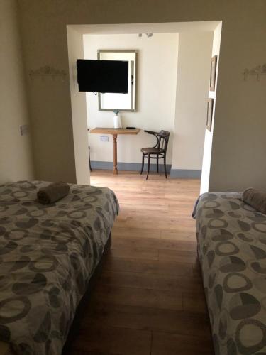 a room with two beds and a table and a television at The Snug, Ardfert Village in Ard Fhearta