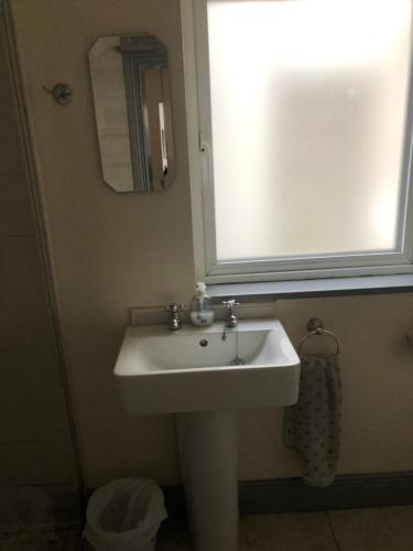 a bathroom with a white sink and a mirror at The Snug, Ardfert Village in Ard Fhearta