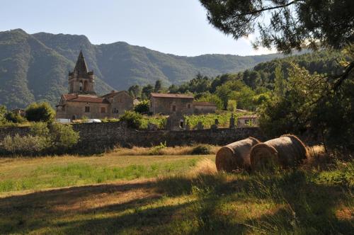 un champ avec des bottes de foin devant une église dans l'établissement Mas d'Entraygues, à Gravières