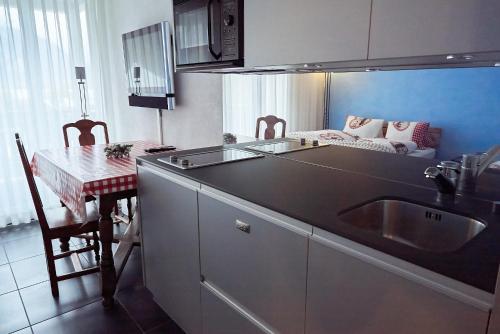 una cucina con lavandino e tavolo con divano di Lake apartment by Interlaken a Därligen