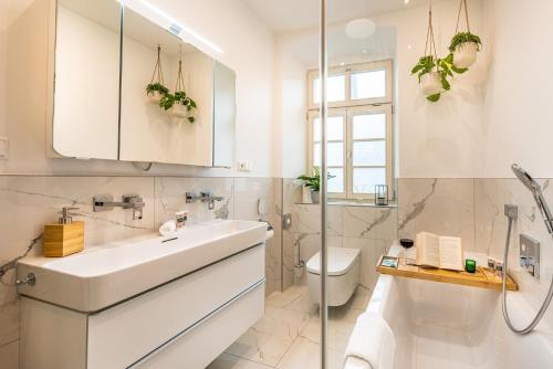 La salle de bains blanche est pourvue d'un lavabo et de toilettes. dans l'établissement VIVID Luxuriöses Apartment Ludwigsburg - Blühendes Barock - Forum - Schloss - EM2024 UEFA, à Ludwigsbourg