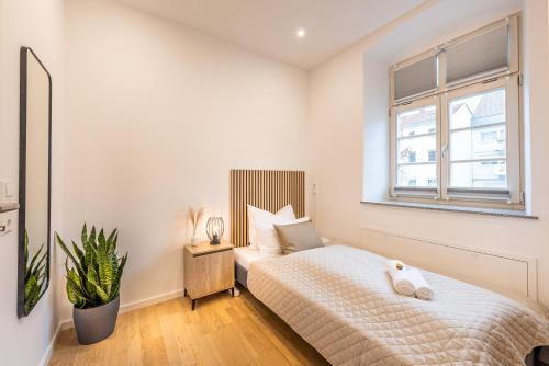 a white bedroom with a bed and a window at VIVID Luxuriöses Apartment Ludwigsburg - Blühendes Barock - Forum - Schloss - EM2024 UEFA in Ludwigsburg