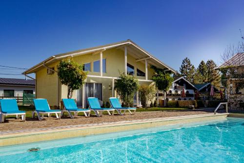 a house with blue chairs and a swimming pool at Casa Augsburg in Băneşti
