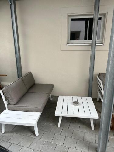 eine Veranda mit einer Bank, einem Tisch und einem Fenster in der Unterkunft Boardinghouse Rheinfelden 1 in Rheinfelden