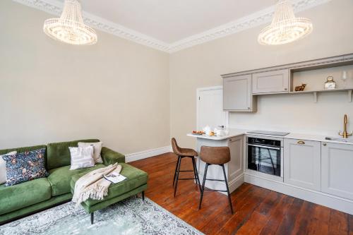 a living room with a green couch and a kitchen at Alfred Apartment - Beautiful Central Bath Location in Bath