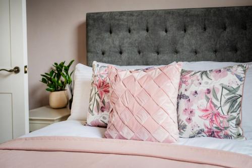 Una cama con almohadas rosas y blancas. en Alfred Apartment - Beautiful Central Bath Location en Bath