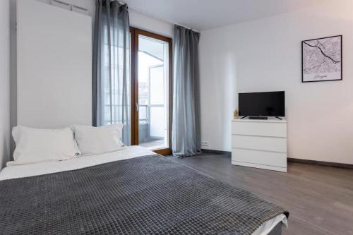 a white bedroom with a bed and a television at Urbannestgroup - Old town studio S27 in Warsaw