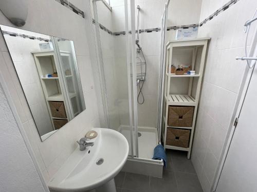 une salle de bain blanche avec un lavabo et une douche dans l'établissement Pavillons Saint Pierre, à Saint-Germain-en-Laye