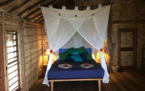 Tanna friendly bungalow في Lénakel: غرفة نوم بسرير مع مظلة