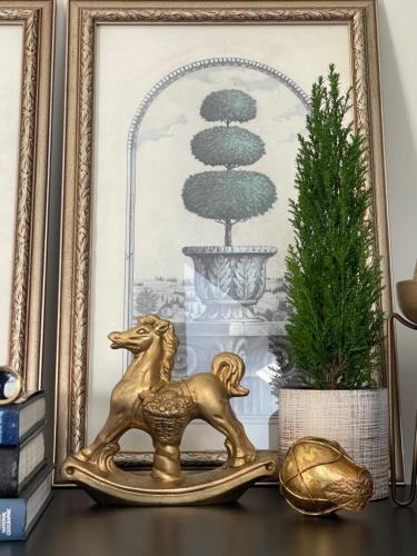 a gold horse statue sitting on a table next to a picture at Mėta House in Merkinė