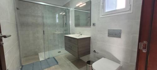 a bathroom with a shower and a toilet and a sink at Sabbia Suites Blue in Costa Teguise