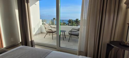 a bedroom with a balcony with a view of the ocean at Sabbia Suites Blue in Costa Teguise