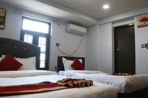 Habitación con 2 camas con almohadas rojas y ventana. en Hotel Darshan, en Surkhet