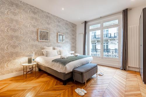 sypialnia z dużym łóżkiem i dużym oknem w obiekcie Sweet Inn - Triangle d'Or w Paryżu