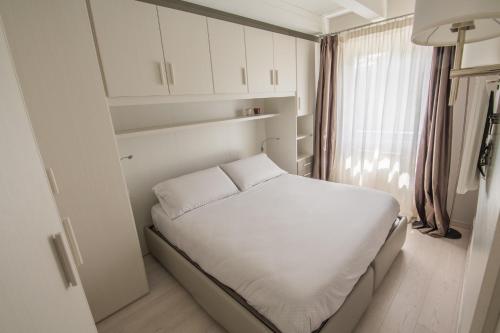 Un pequeño dormitorio con una cama blanca y una ventana en BILOCALE BELLA VISTA, en Temù