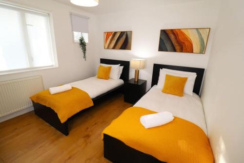 a room with two beds with orange cushions at Hutchcomb Villa, 4 Bed Luxury House,Oxford+Parking in Oxford