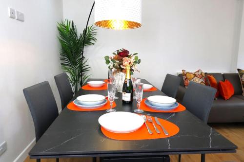 a dining room table with a black table with orange chargers at Hutchcomb Villa, 4 Bed Luxury House,Oxford+Parking in Oxford