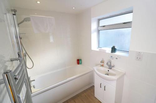 a white bathroom with a tub and a sink at Hutchcomb Villa, 4 Bed Luxury House,Oxford+Parking in Oxford