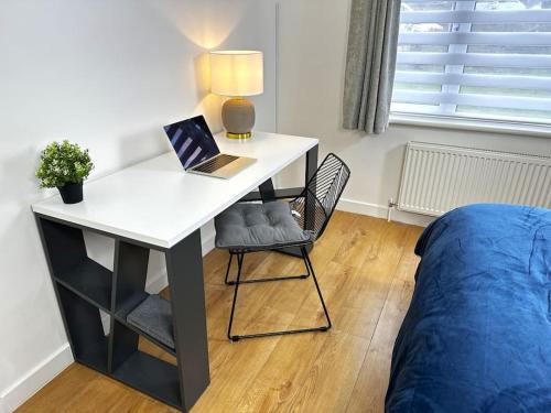 a desk with a laptop and a bed in a room at Hutchcomb Villa, 4 Bed Luxury House,Oxford+Parking in Oxford