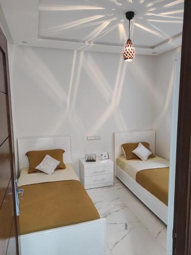 2 Betten in einem Zimmer mit weißen Wänden in der Unterkunft La Joie Al Jadid in Nador