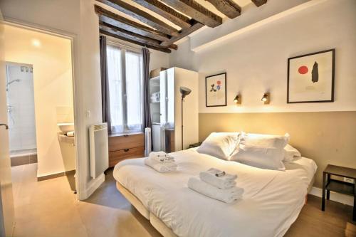 a bedroom with a white bed with towels on it at 1 bedroom apt only 15 min walk to The Louvre in Paris