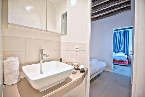 - une salle de bains blanche avec lavabo et une chambre dans l'établissement 1 bedroom apt only 15 min walk to The Louvre, à Paris