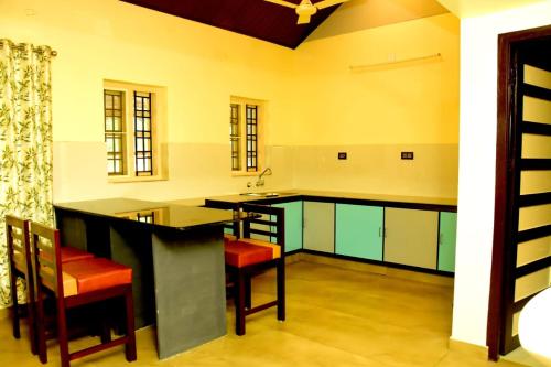 a kitchen with an island with red chairs in it at Manjippuzha Nature Space in Alleppey