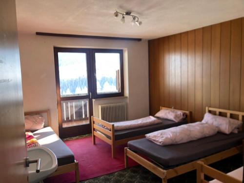 a small room with two beds and a window at Appartement Grünfelder in Oberperfuss