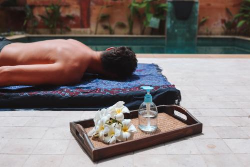 a man laying on a towel with a tray with a bottle of water at Alanta Pool Villa in Ko Lanta